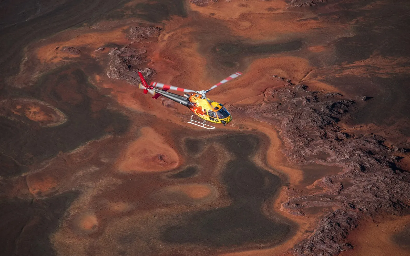 Ein Helikopter über dem Lavafeld des Piton de la Fournaise auf Reunion Island